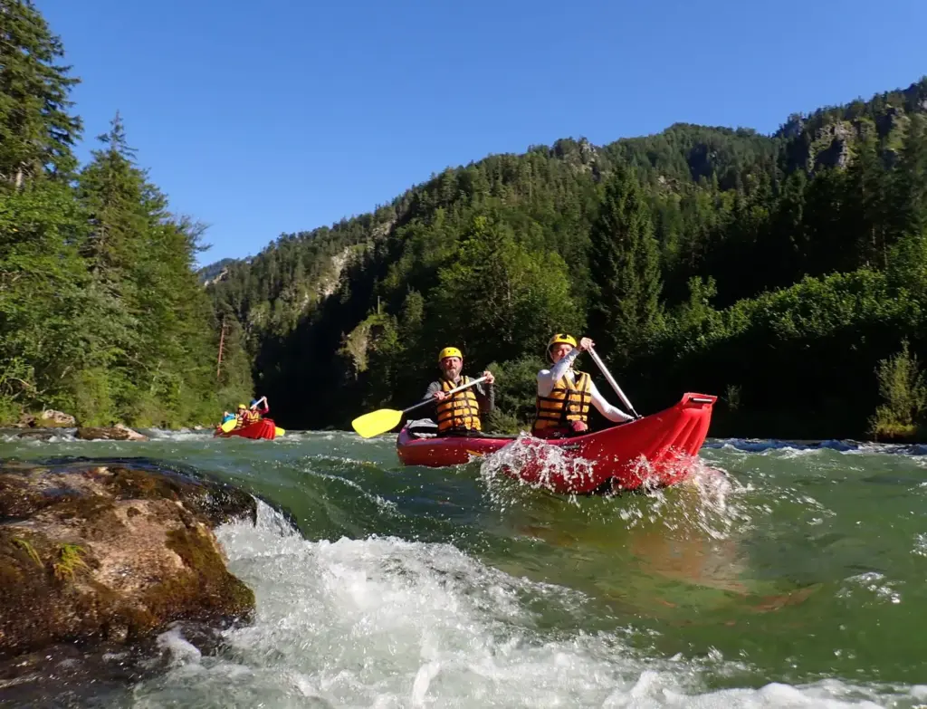 Aufregendes Kajak-Abenteuer auf einem schnell fließenden Gebirgsfluss inmitten üppiger Vegetation. Perfekt für Nervenkit