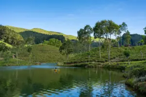 Idyllische Szene einer Person, die auf einem ruhigen See Kajak fährt, umgeben von üppigen grünen Hügeln und heiteren Lan